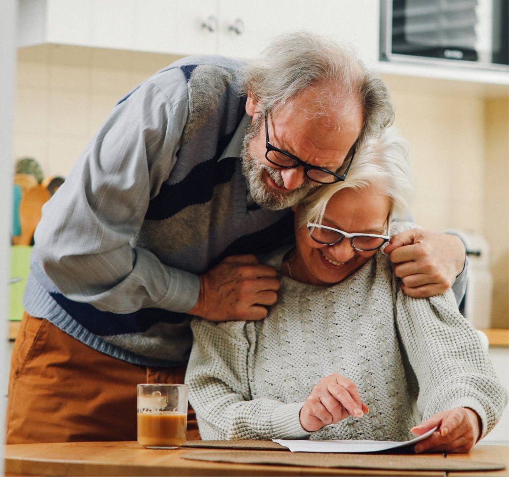 elderly couple hugging and looking at a form